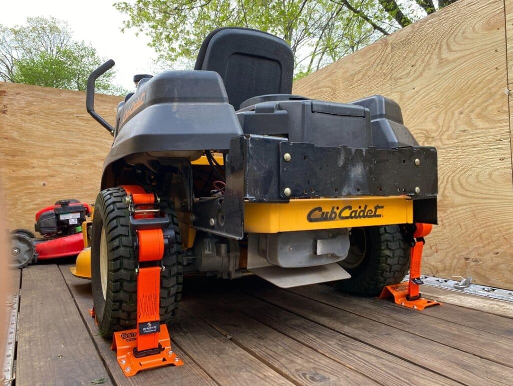 black with yellow accents lawn tractor secured by Strapinno retractable ratchet straps