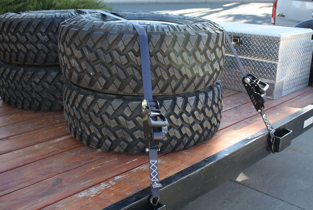 large tires secured on a truck bed using retractable ratchet straps