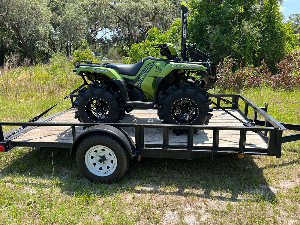 lime green UTV secured by black Strapinno retractable ratchet straps on truck bed