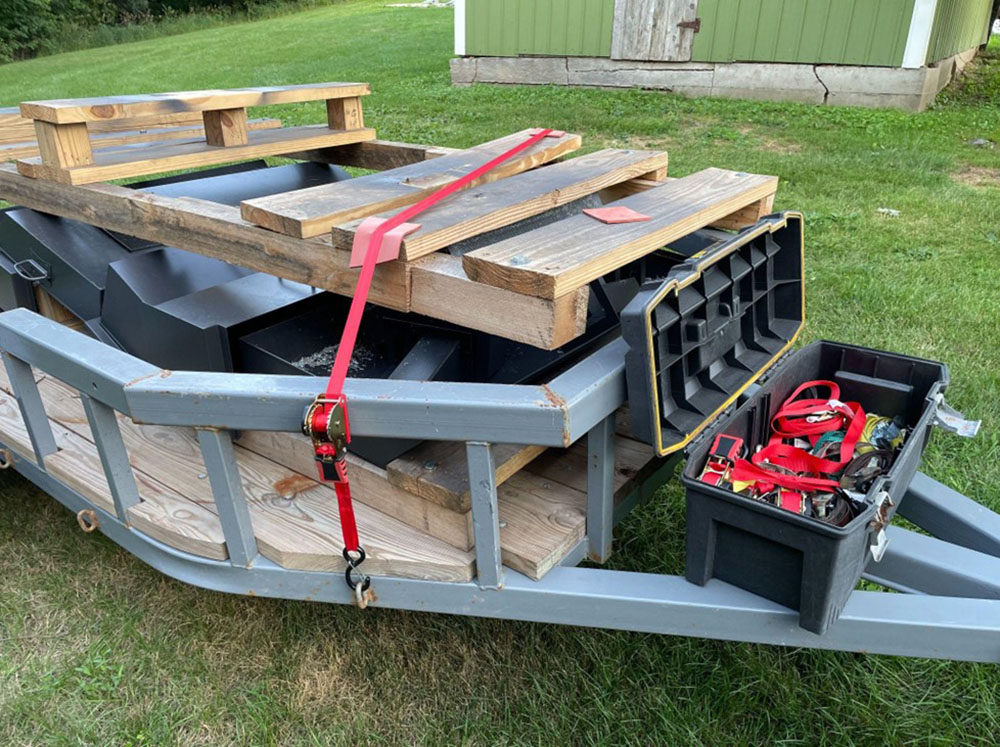 wooden cargo attached in a trailer using red retractable ratchet straps