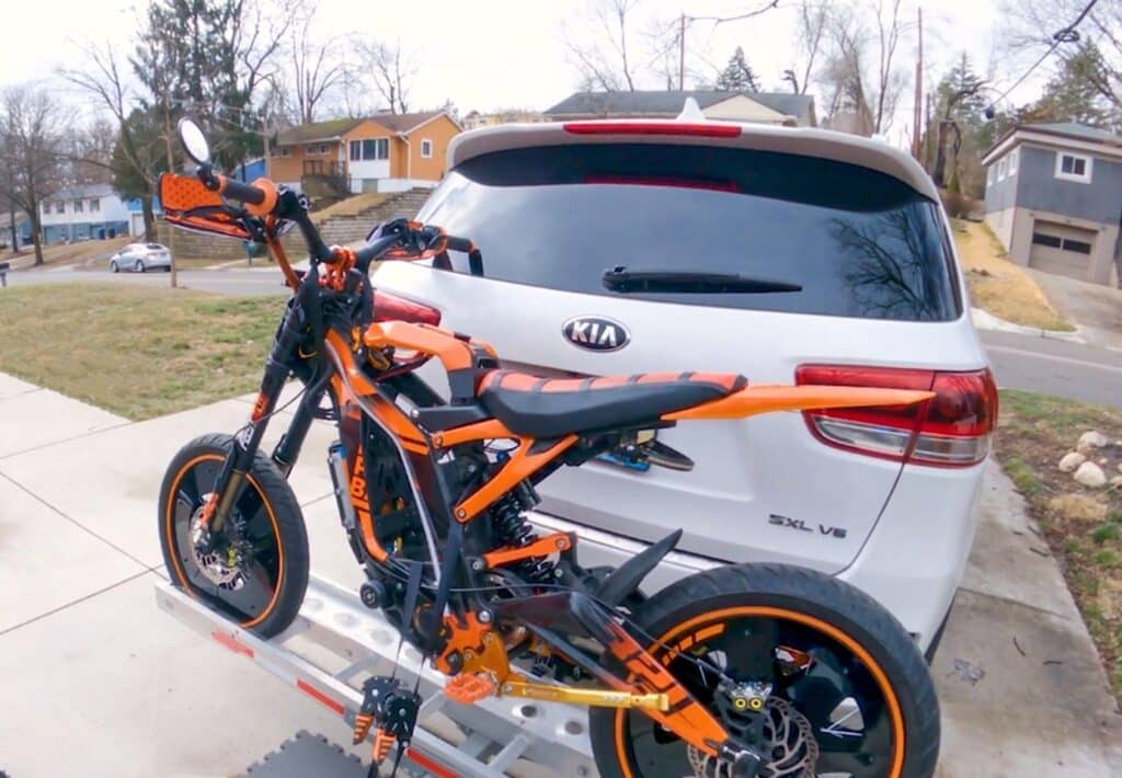 e-bike in orange and black secured at the back of a vehicle using Strapinno retractable ratchet straps