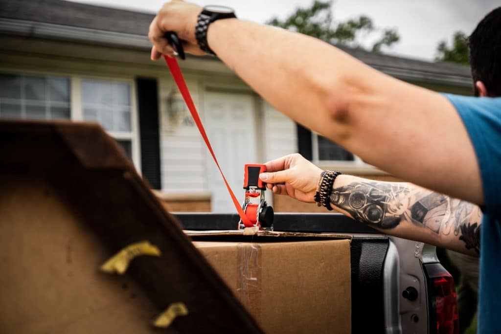 person securing a large box ona pickup truck bed using Strapinno retractable ratchet straps