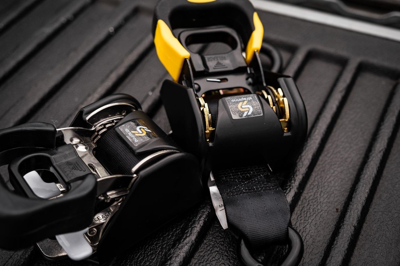 Selective focus photography of Strapinno retractable ratchet straps on a black truck bed