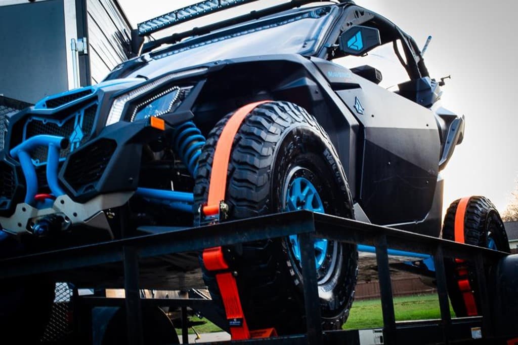 black ATV secured with Strapinno retractable ratchet straps on a trailer