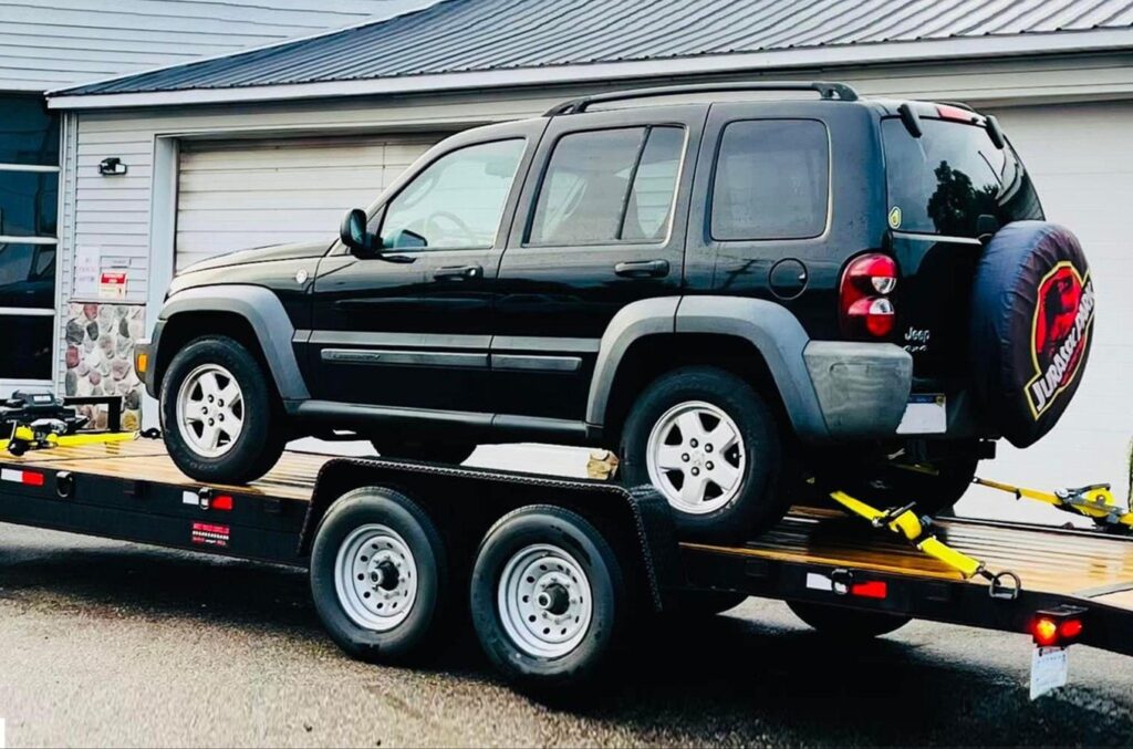 black SUV secured on a trailer bed using Strapinno retractable ratchet straps