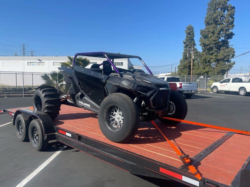 black ATV secured on a trailer truck bed using Strapinno's retractable ratchet straps