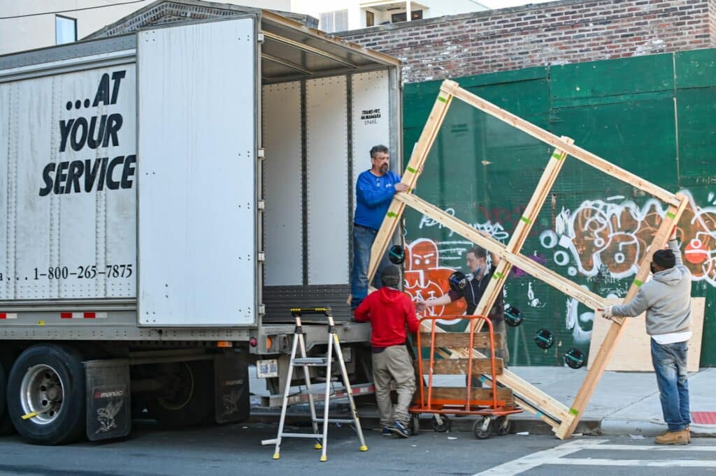 four men unloading cargo from a big mover truck
