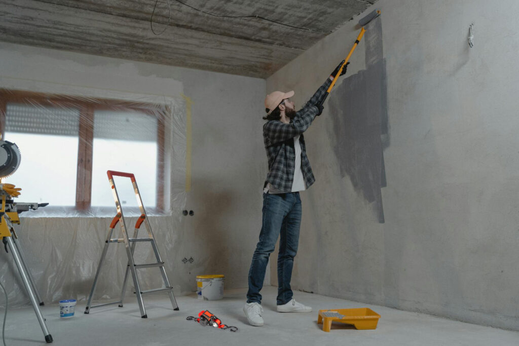 man painting wall with Strapinno's retractable ratchet straps on the floor by his feet