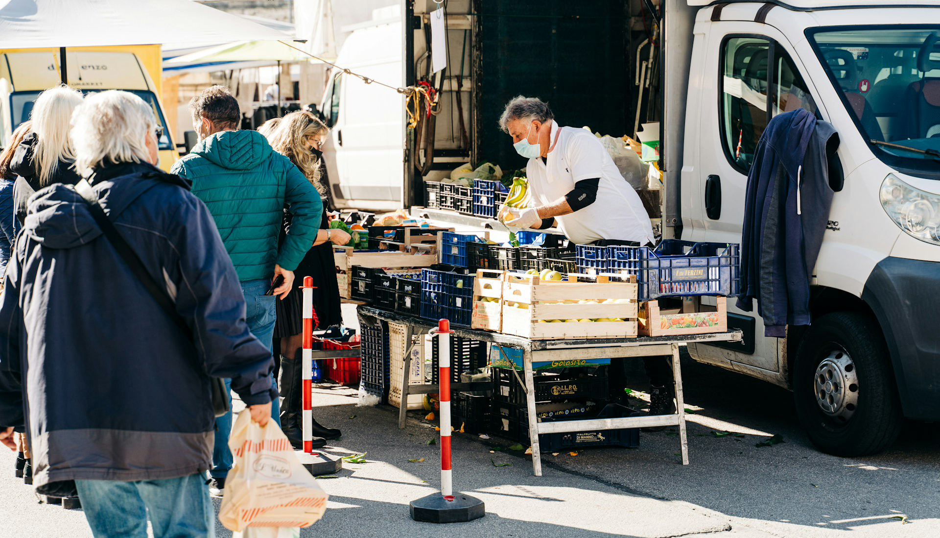 a group of people standing around a table Farmers market stall