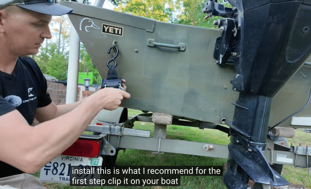 clipping a retractable boat tie down strap onto a boat