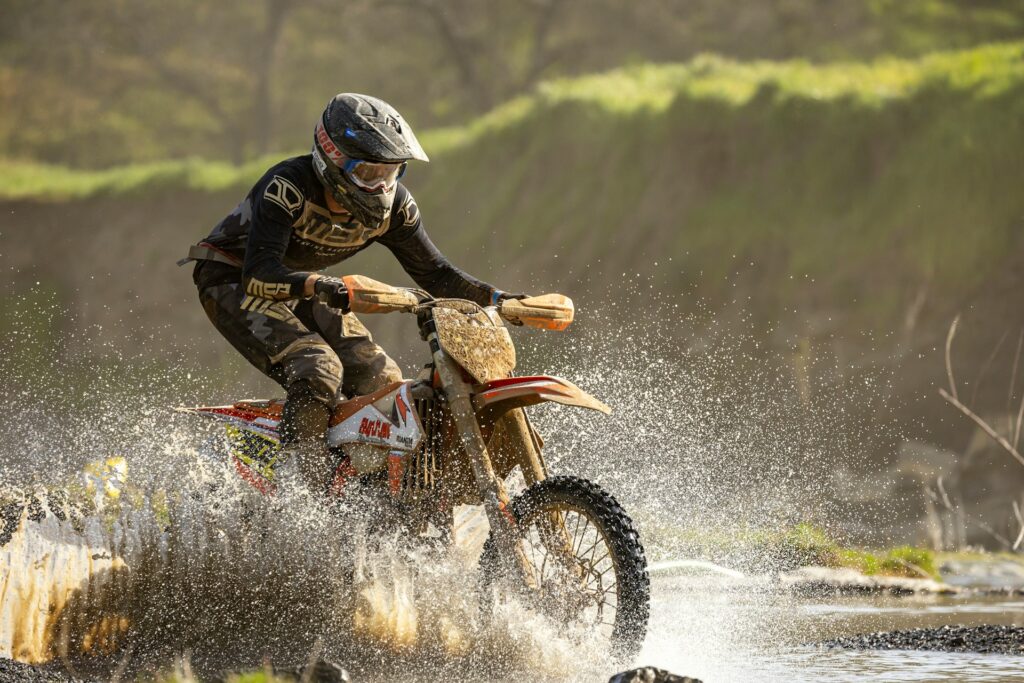 a man riding a dirt bike through a river