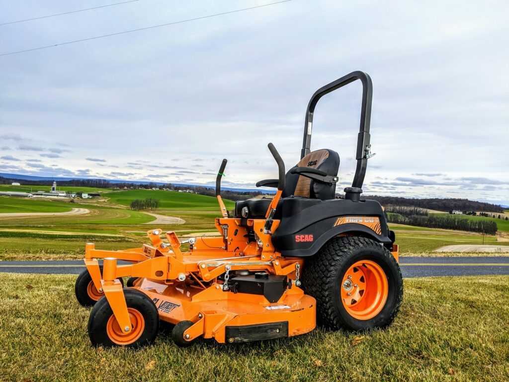 orange lawn mower parked on the side of a road