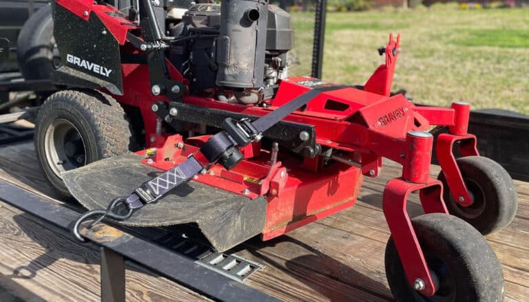 red lawn mower secured to a trailer using Strapinno retractable ratchet straps