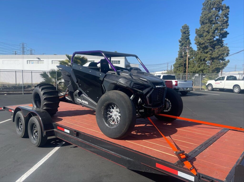 black atv secured on a trailer using Strapinno's retractable ratchet straps on a sunny day