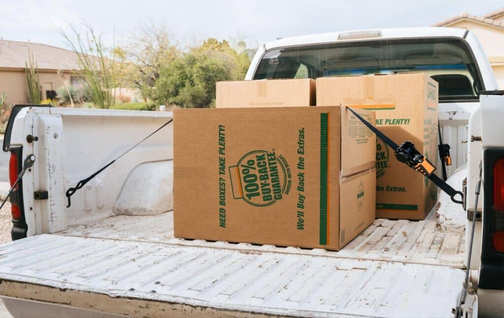 boxes on a white pickup truck's trailer secured by Strapinno's black retractable ratchet straps